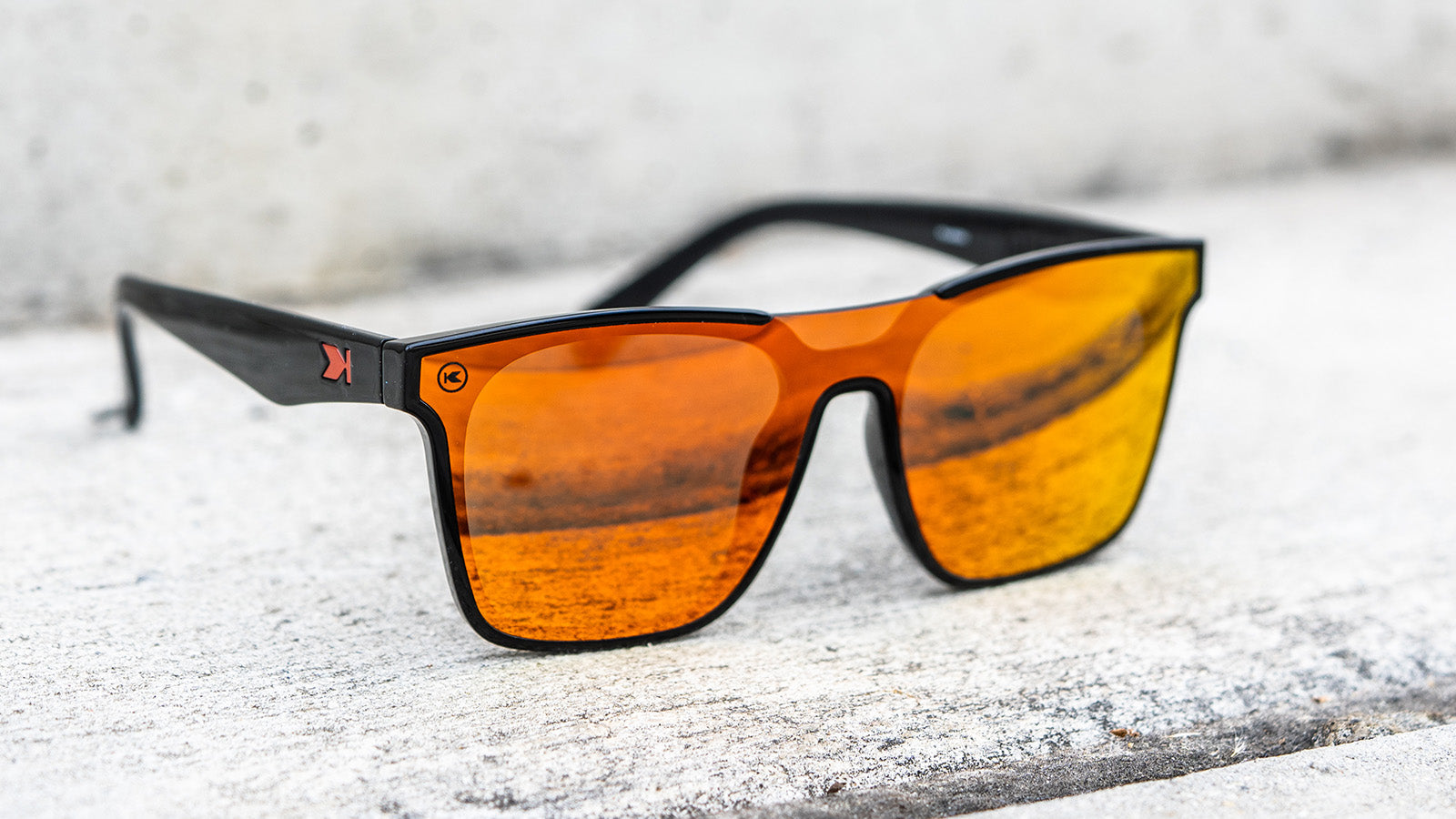 Sunglasses with a black frame with polarized orange lenses, flyover