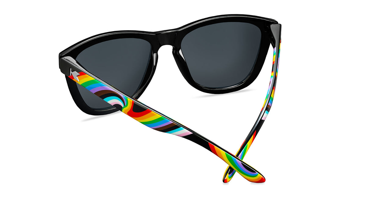 Sunglasses with Glossy black fronts with rainbow accent at bottom, Progress Pride color swirl across arms Silver K-logos Polarized rainbow lenses