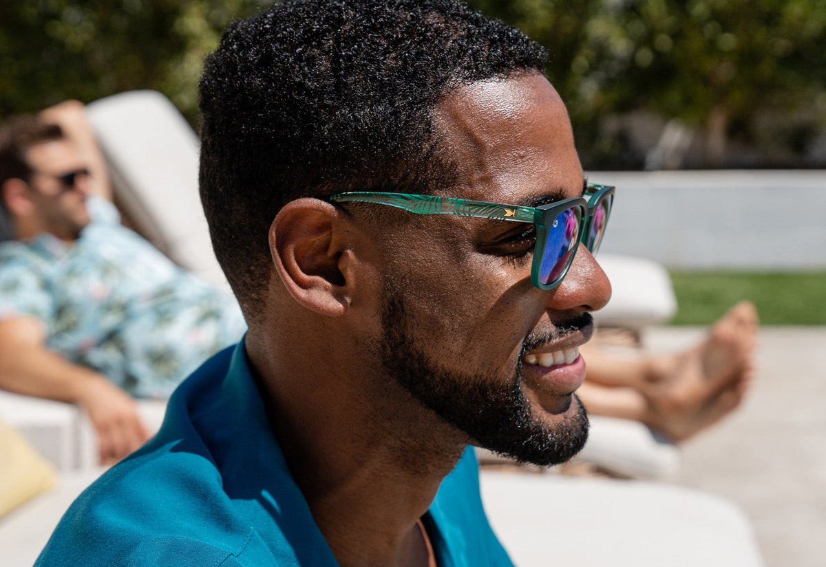 Sunglasses with green fronts, green palm tree arms, and polarized green lenses, model